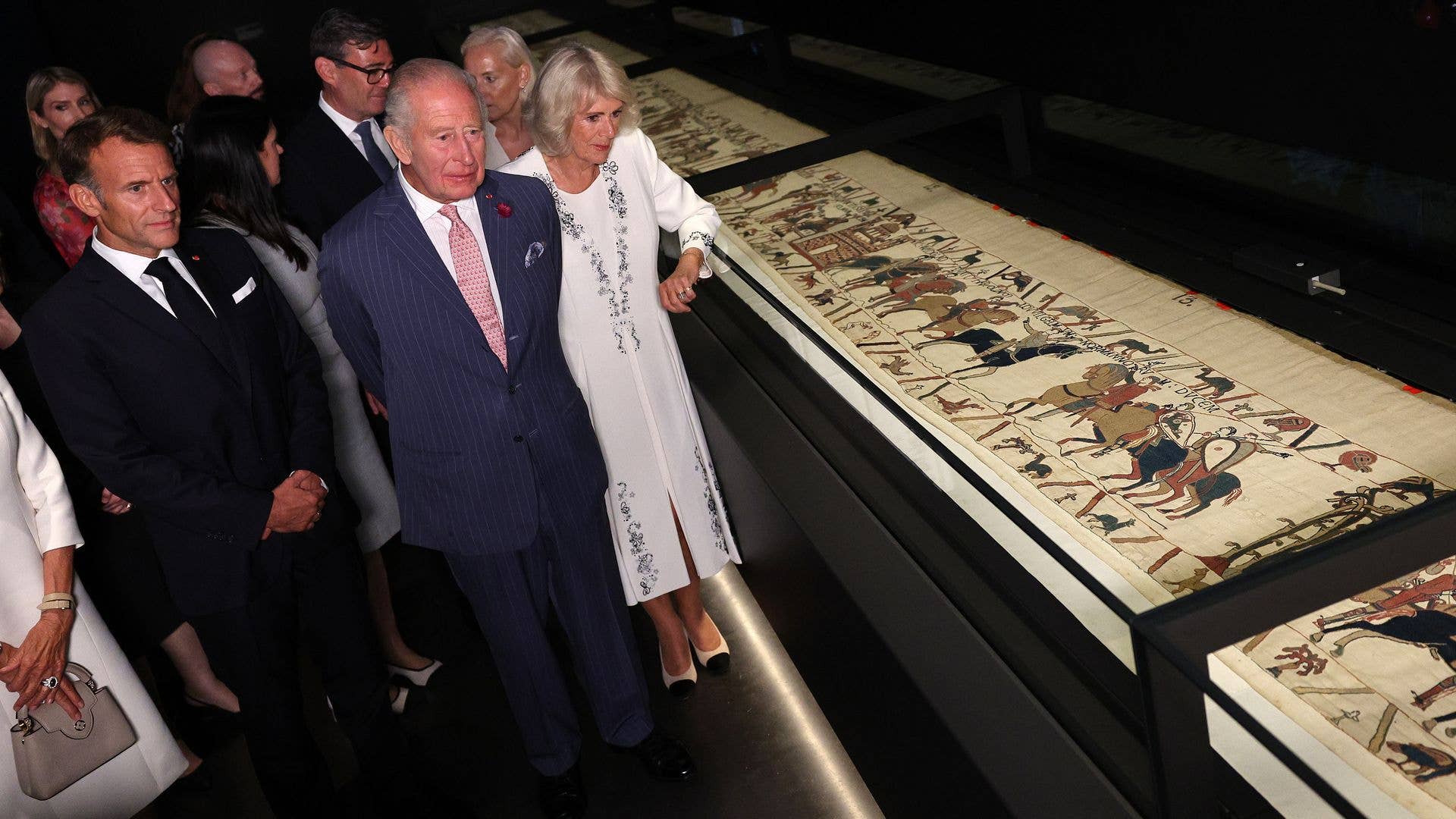 King Charles and Queen Camilla view an exhibit with Emmanuel Macron and others.