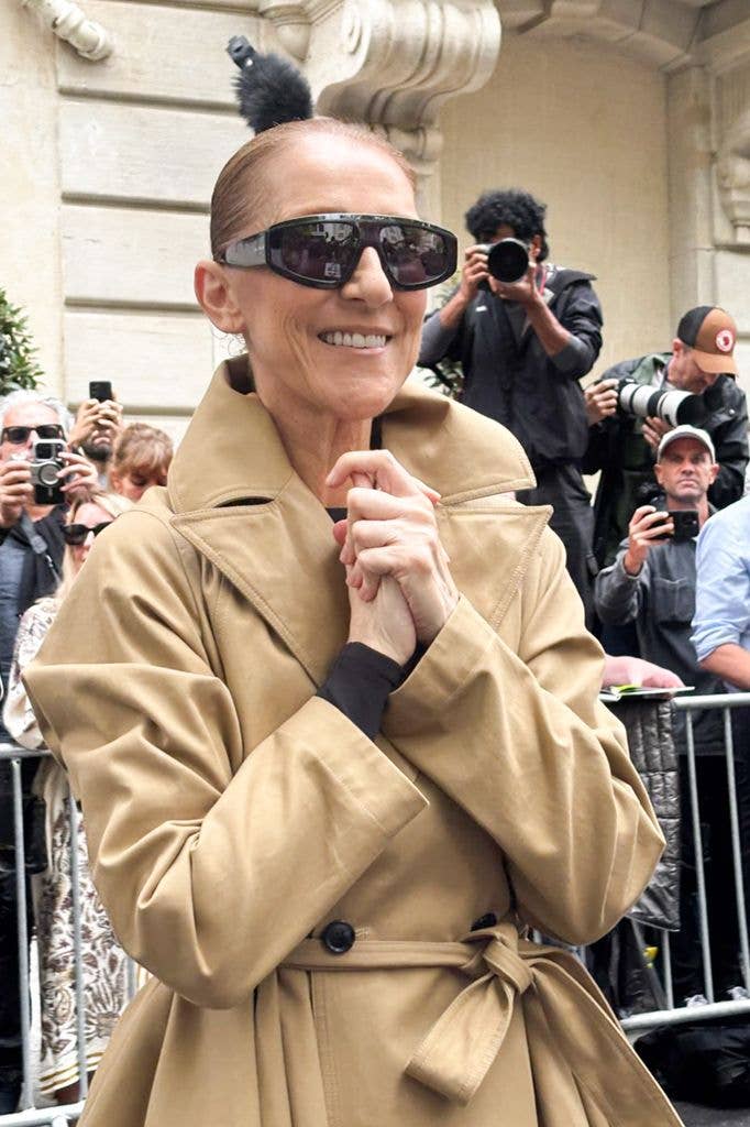 Celine Dion wearing a camel-colored trench coat, dark sunglasses, in Paris