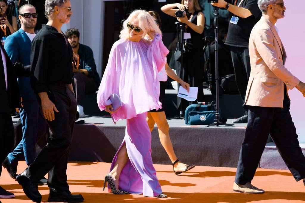 Pamela Anderson wearing a purple outfit and walking on the red carpet at Venice Film Festival