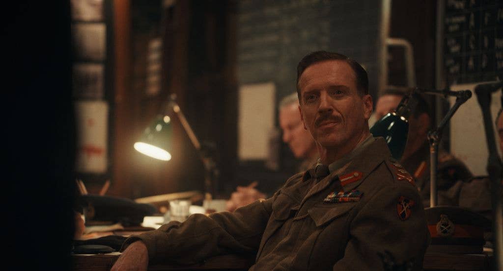 Damian Lewis in military uniform with medals, sitting at a desk in an office.