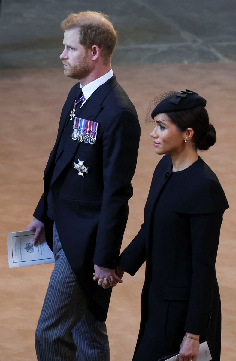 Prince Harry, Duke of Sussex and Meghan, Duchess of Sussex walk as procession with the coffin of Britain's Queen Elizabeth arrives at Westminster Hall from Buckingham Palace