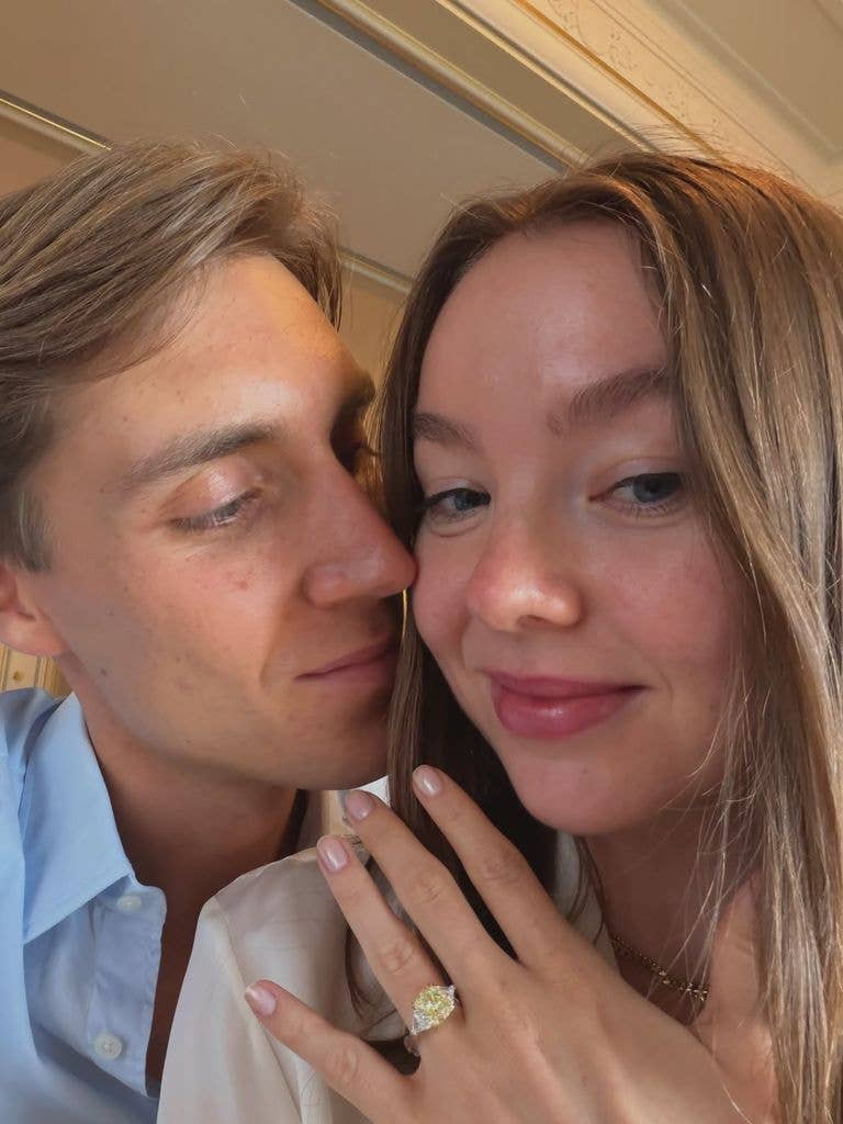 A man and a woman, possibly Princess Alexandra of Hanover, are close together, smiling. The woman shows a ring on her finger.