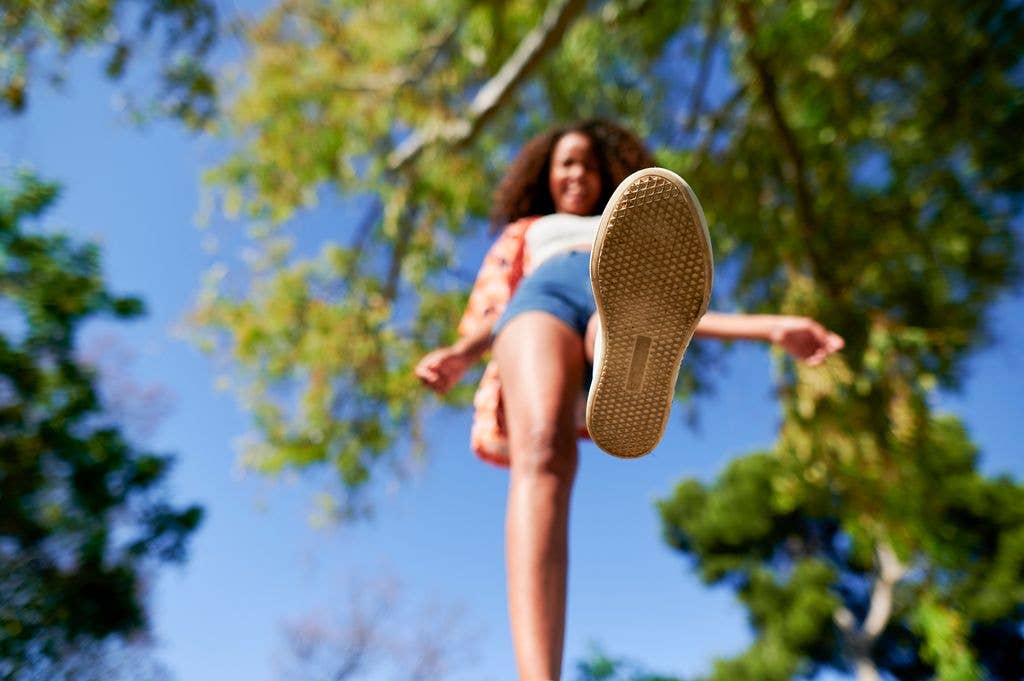 Young woman stepping with shoe sole visible, creating an interesting perspective outdoors