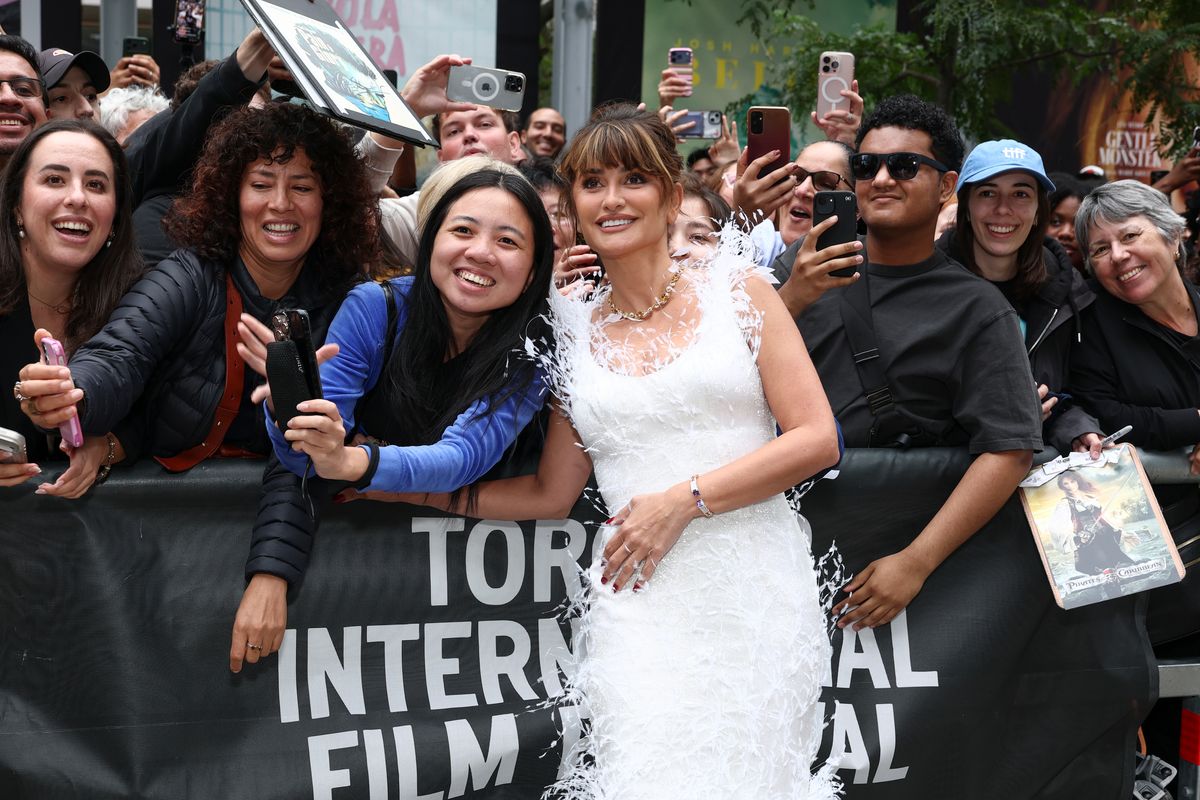 Cruz paired her statement white look with gold jewelry, red nails and an elegant updo with her signature bangs.