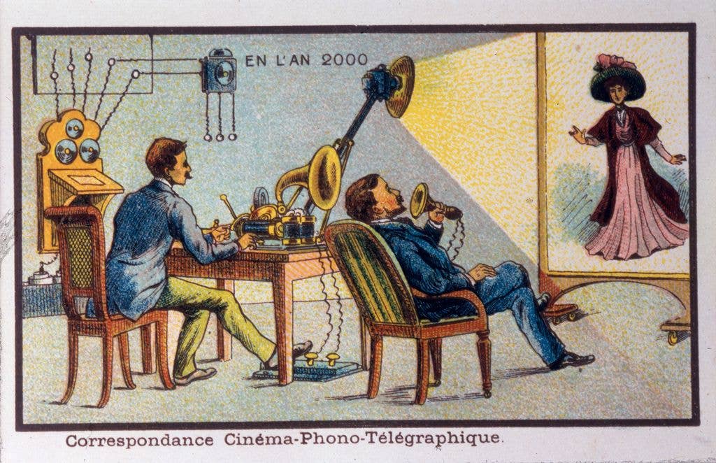 An antique colour illustration shows two men seated at a desk with telegraph-like equipment, watching a projected image of a woman on a screen, under the caption 'En l'An 2000'.