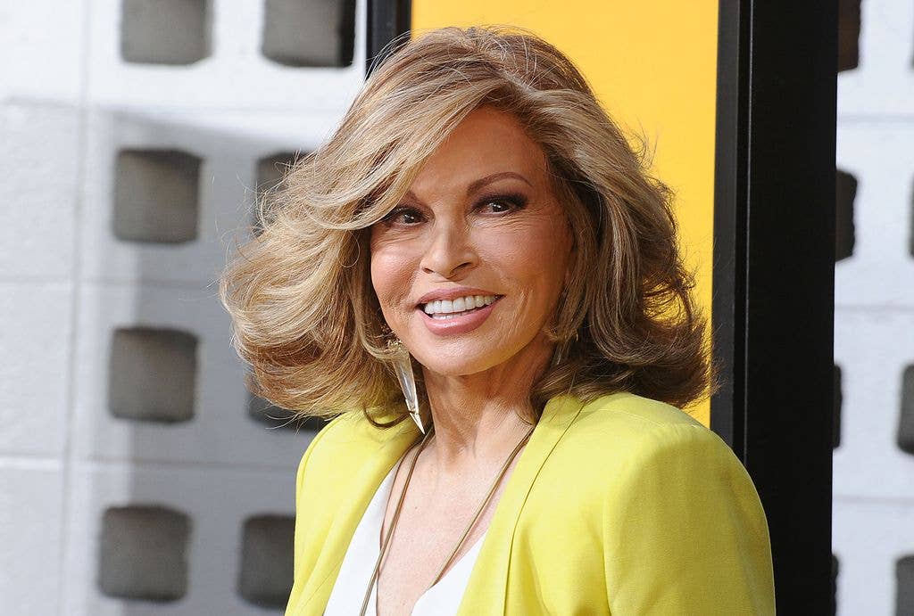 Raquel Welch wears a yellow blazer and smiles to the side.