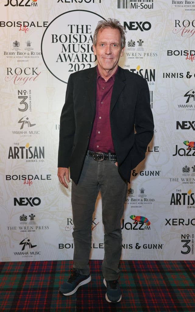 Hugh Laurie smiling for a red carpet photo
