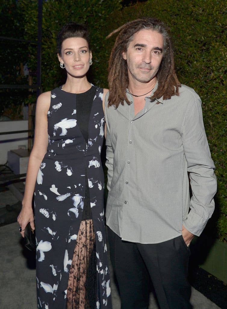 Jessica Paré stands next to partner John Kastner, both smiling.