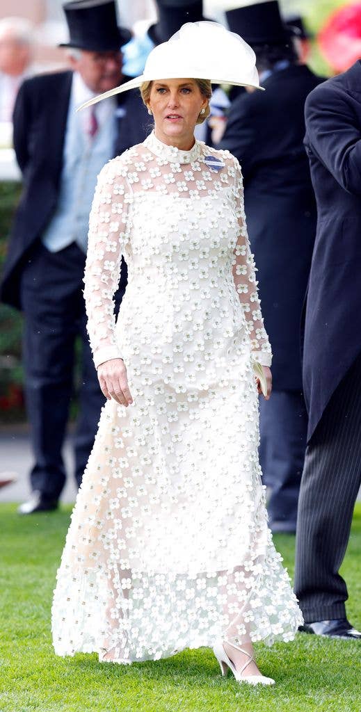 Sophie wears a white lace dress with matching hat