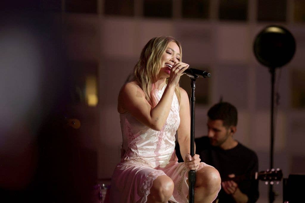 Hilary Duff sitting on a stool and singing
