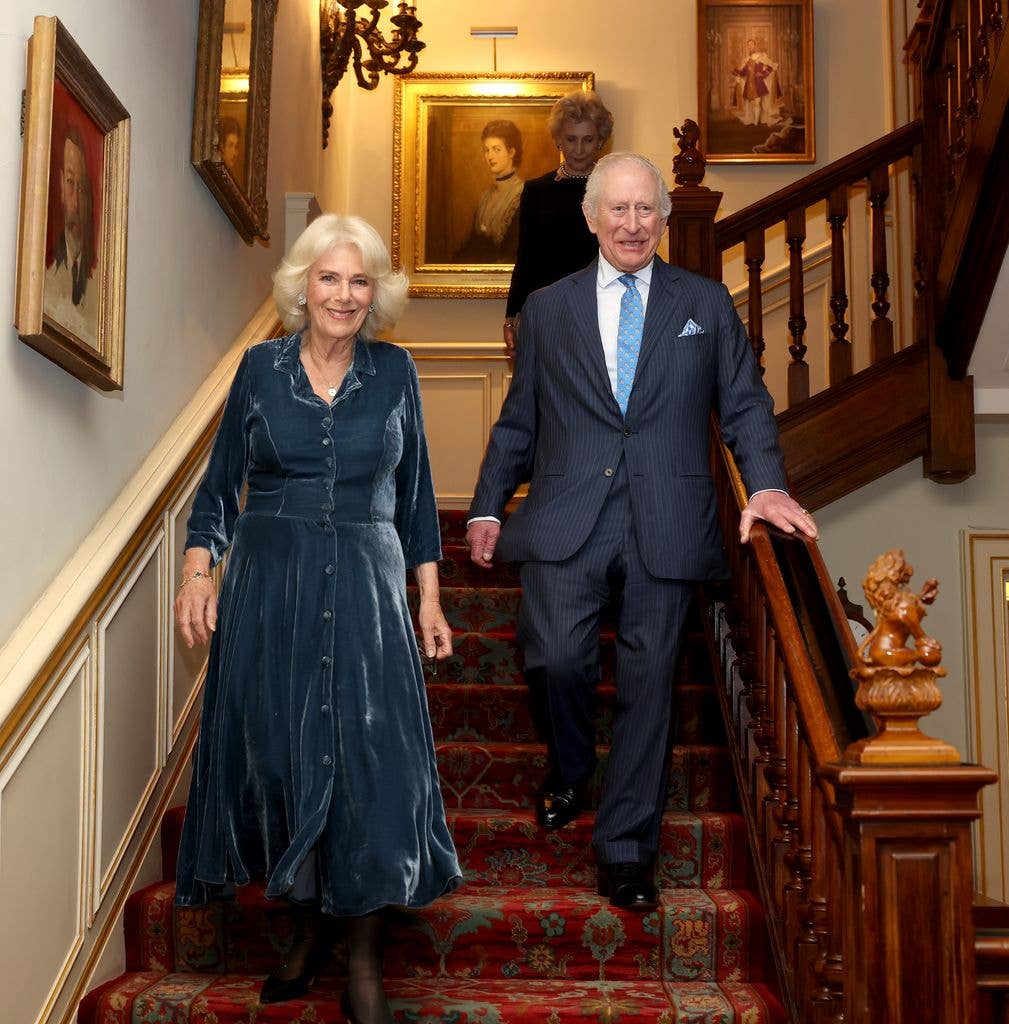 King Charles III and Queen Camilla walk down the stairs during a reception to mark the launch of the Queen's reading room medal at Clarence House