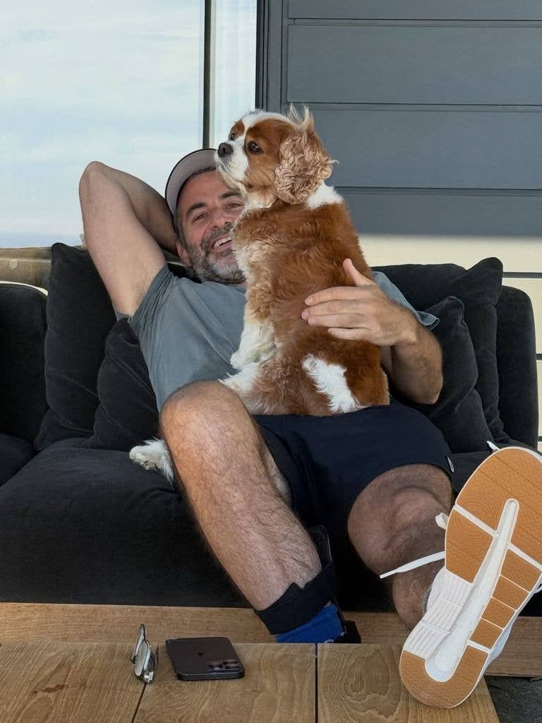 Jim Curtis reclines on a couch with a dog perched on him, shared on Instagram