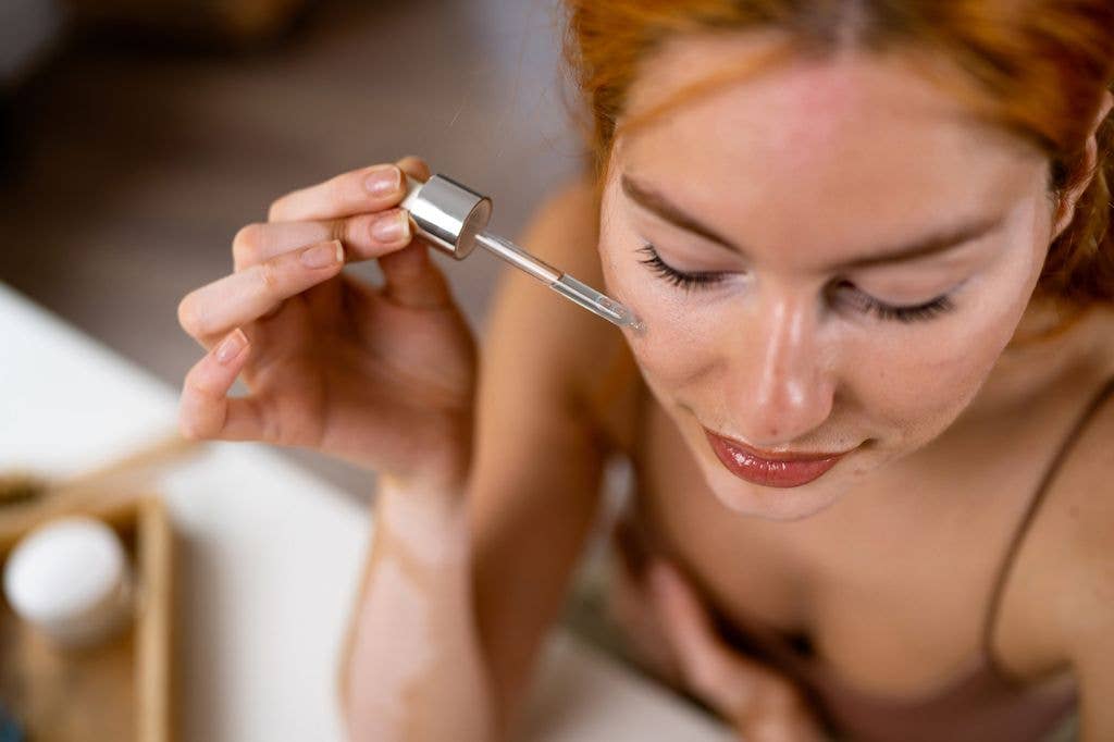 Best fake tan for redheads and pale skin. Young redhead Caucasian woman, with vitiligo and acne on her face, doing a skin care in her home