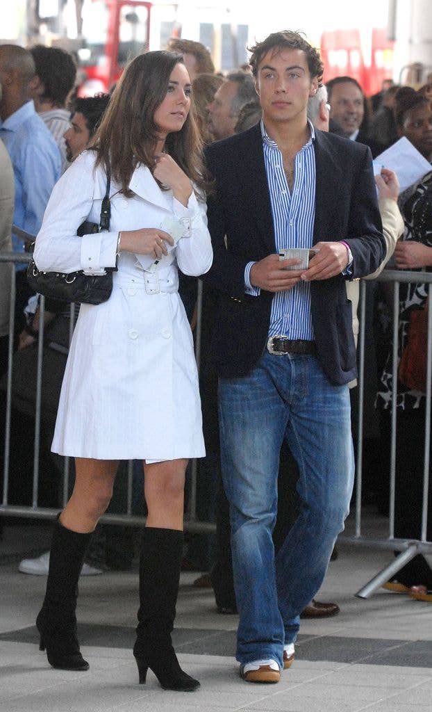 James Middleton and a woman in white coat walk through a crowd, he holds a phone.