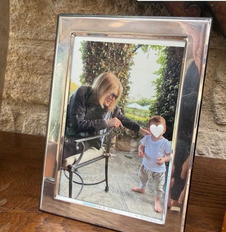 Silver frame shows Gloria Steinem sitting, holding a toddler's hand.