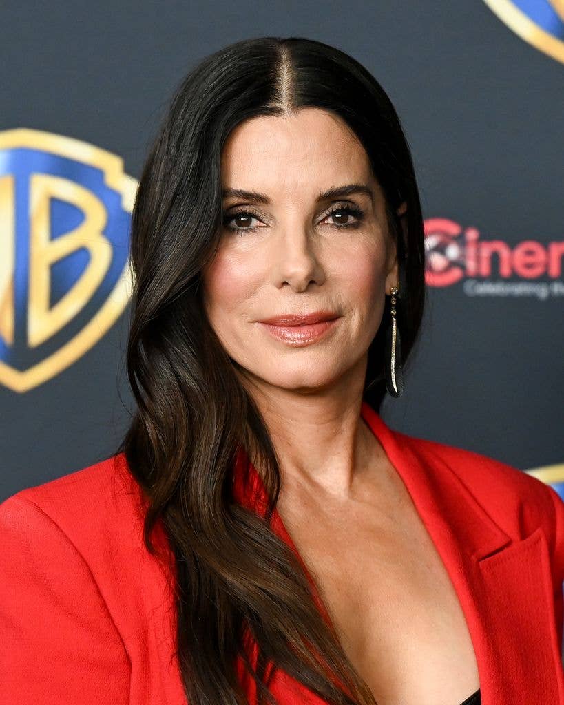 Sandra Bullock in a red blazer, smiling at the camera.