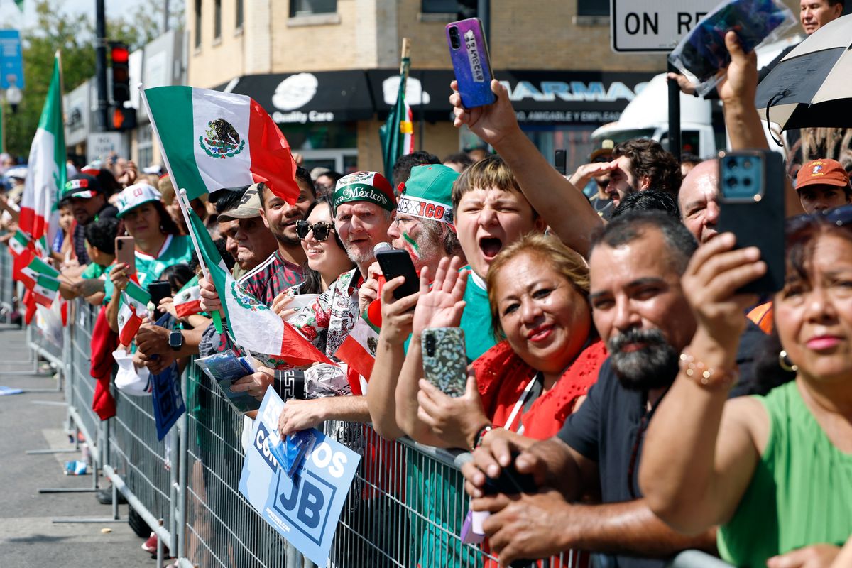 Attendees wave Mexico flags as they watch the Mexican Independence Day parade