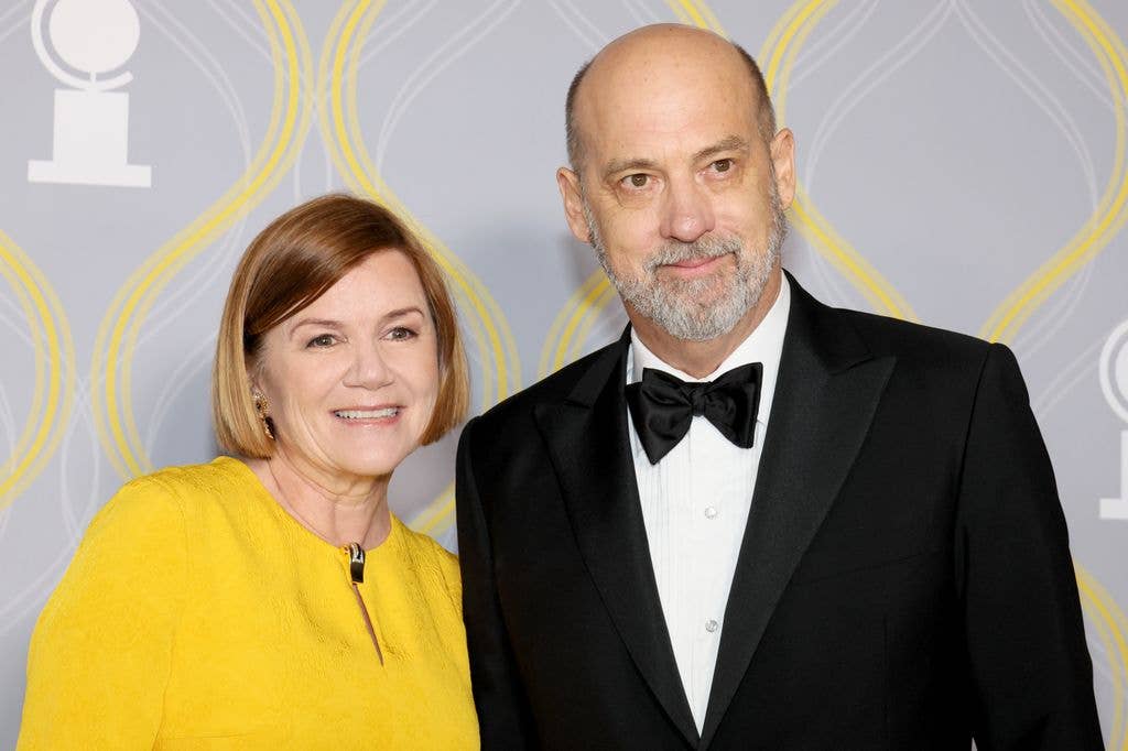 Mare Winningham in a high neck yellow dress and Anthony Edwards in a black suit with a black bowtie.