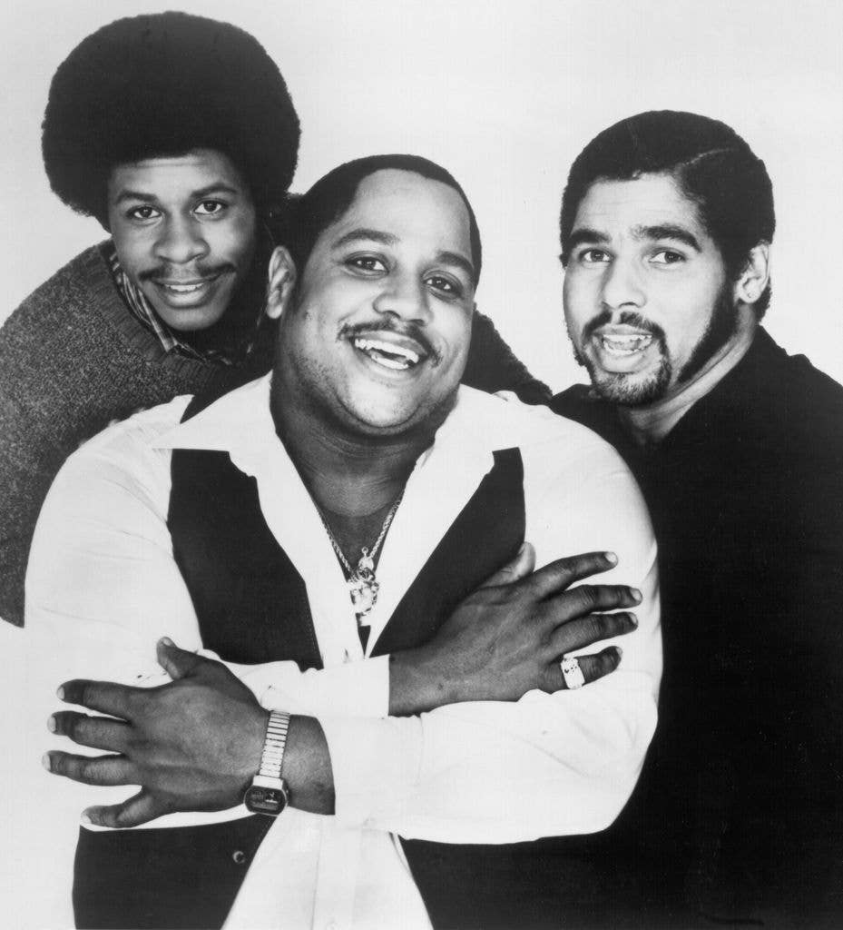 Three men, one of whom is Wonder Mike, smiling and posing for a photo.