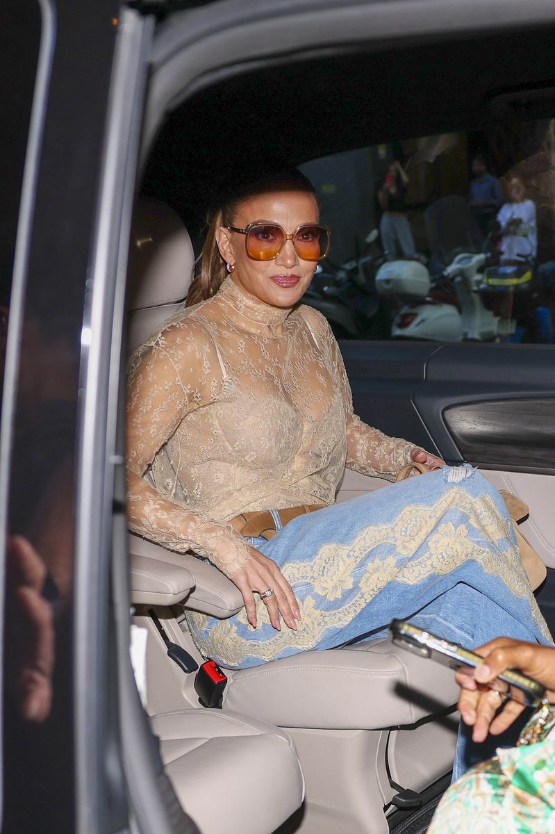 Jennifer Lopez was spotted leaving the Palazzo Parigi luxury hotel during Milan Fashion Week wearing a high-neck, long-sleeved sheer beige lace top subtly revealing a matching bralette