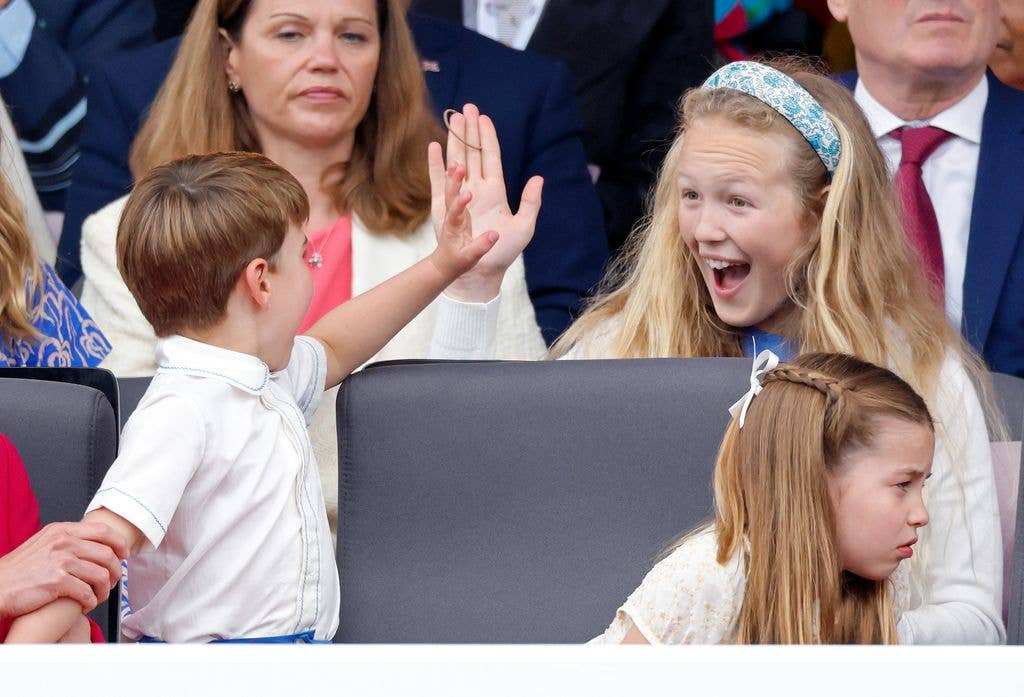 Young boy in white shirt high-fiving a girl with a blue headband, both smiling.