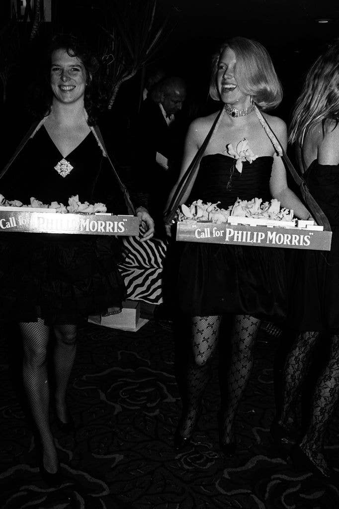 Two cigarette girls carrying trays. 