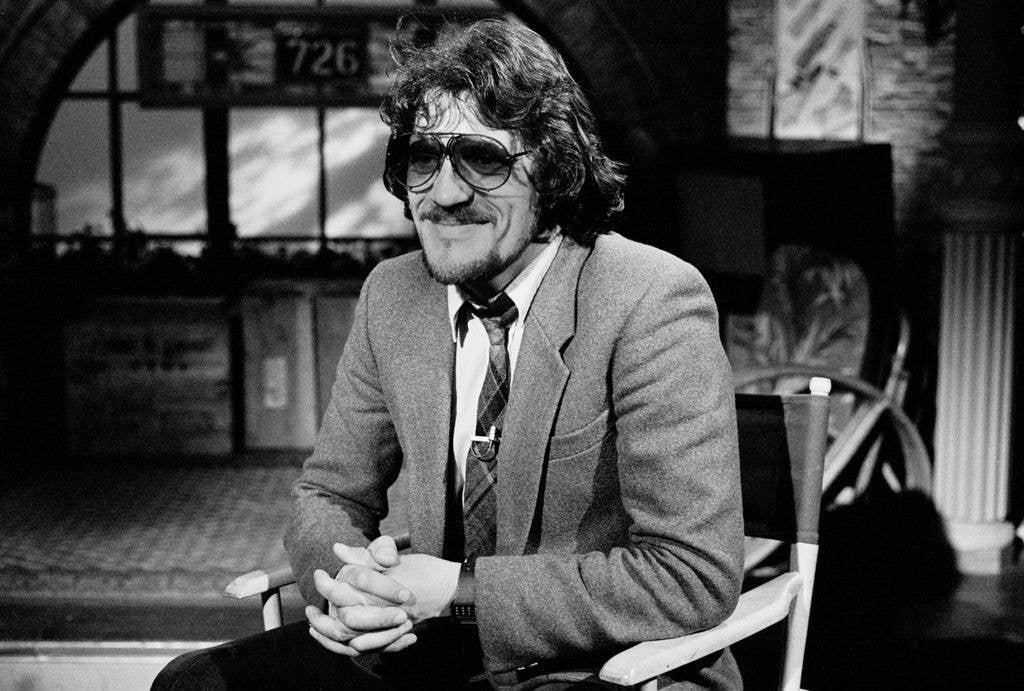 View of British Pop and Rock musician Jim Capaldi (born Nicola James Capaldi, 1944 - 2005) as he sits in a director's chair during an interview on MTV at Teletronic Studios, New York, New York, May 3, 1983. 